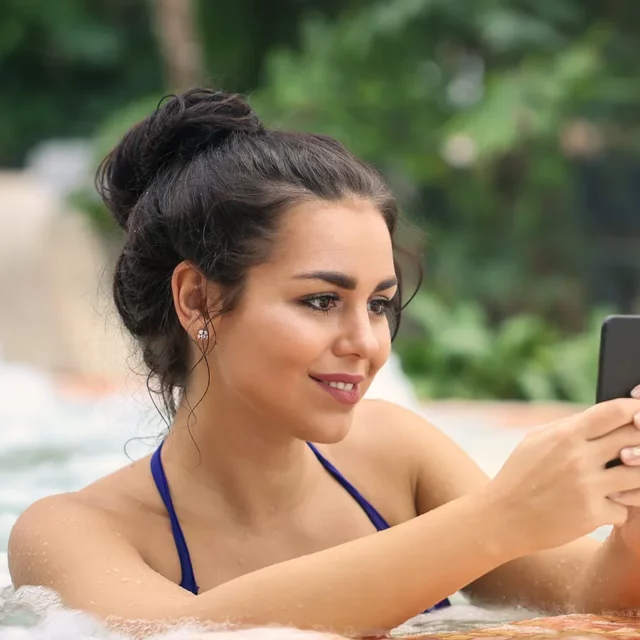 Frau im Whirlpool mit Handy