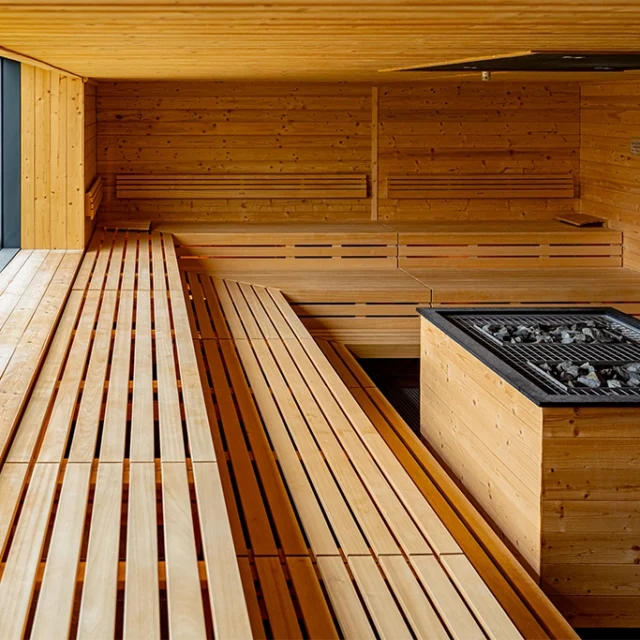 Aufgusssauna mit Holzbänken und Saunaofen in der Mitte